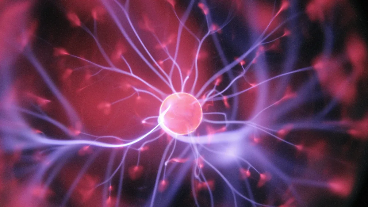 A pink and purple neuron cell with branching extensions, set against a dark background.